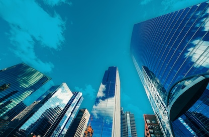 A collection of buildings form a skyline in front of a blue sky