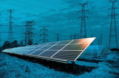 Transmission towers are seen in the background of a solar panel installment